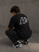 Camiseta oversize HeatCore Future Black negra con logo llama efecto cromado en la espalda, vista de modelo