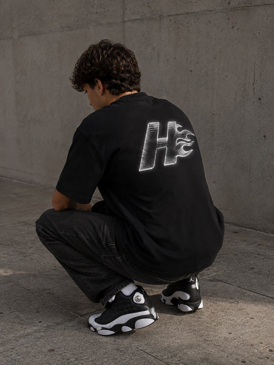 Camiseta oversize HeatCore Future Black negra con logo llama efecto cromado en la espalda, vista de modelo